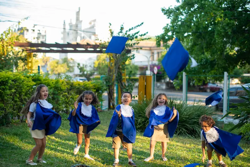 Crianças com toga em formatura infantil quepe para cima