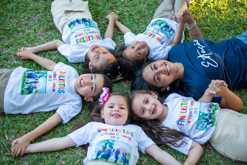 Crianças felizes deitadas na grama sorrindo para foto